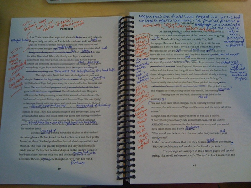 Opened spiral notebook with editorial marks atop typed words